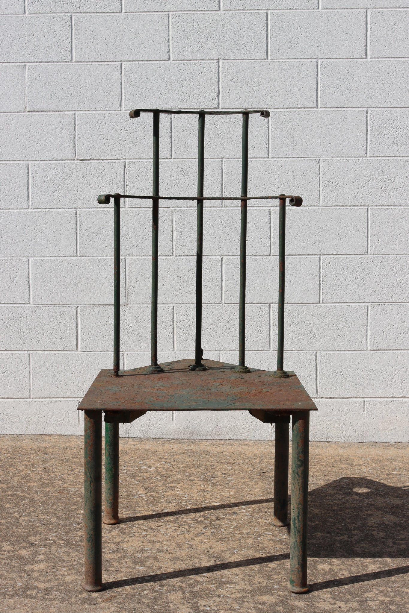 A green-painted and patinated metal chair with back spindles over a shaped seat above four cylindrical legs.